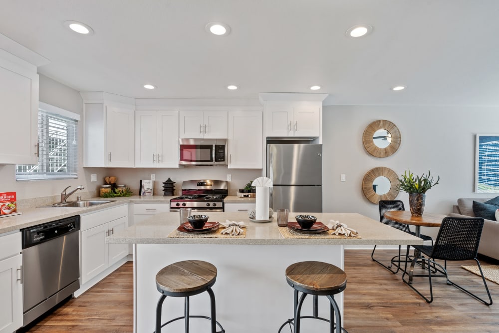Open modern kitchen with a large island with seating at Pinebrook Apartments in Fremont, California
