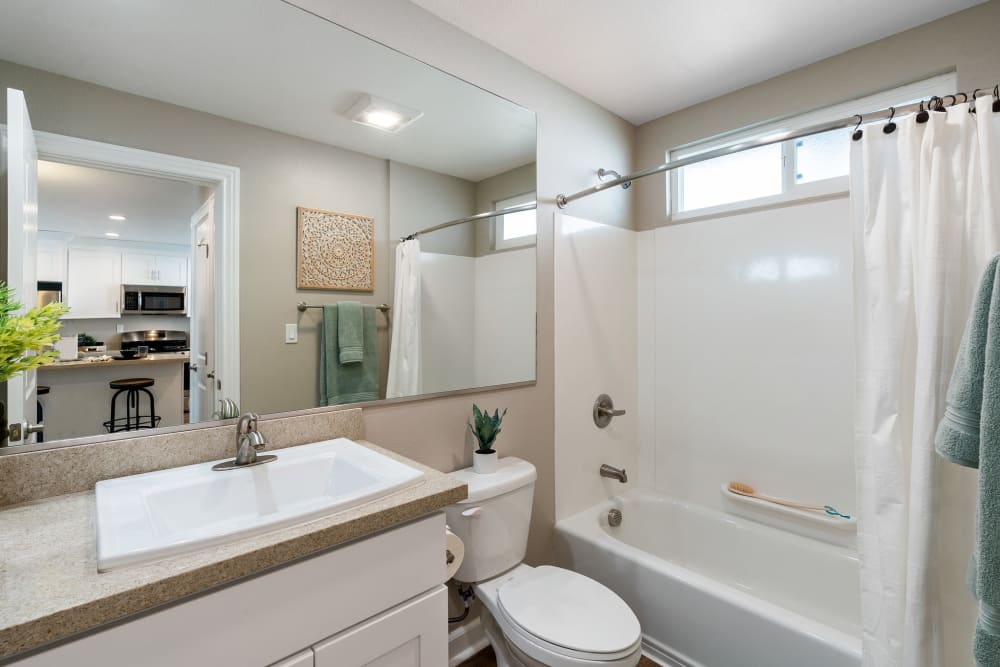 Model bathroom with a tiled tub/shower at Pinebrook Apartments in Fremont, California