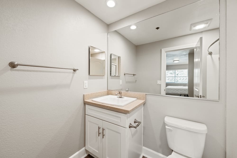 Bathroom with an oversized mirror and white cabinetry at Summerhill Terrace Apartments in San Leandro, California