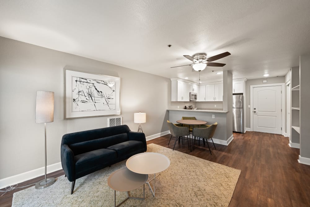 Open layout living area of a model apartment with a ceiling fan and wood-style flooring at Summerhill Terrace Apartments in San Leandro, California