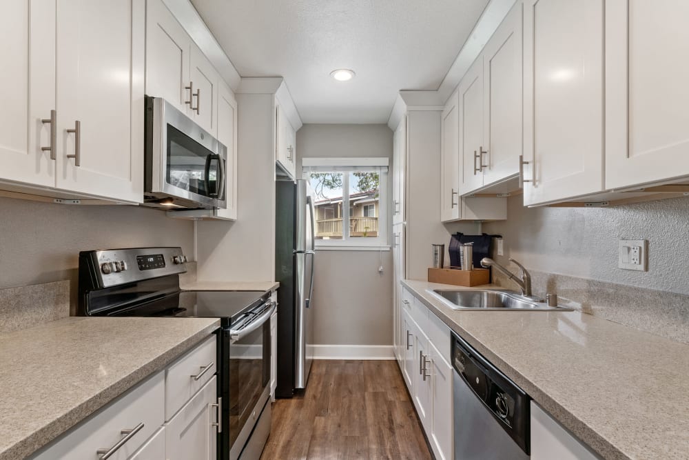 Fully equipped kitchen with white Shaker cabinetry and stainless-steel appliances at Vista Creek Apartments in Castro Valley, California