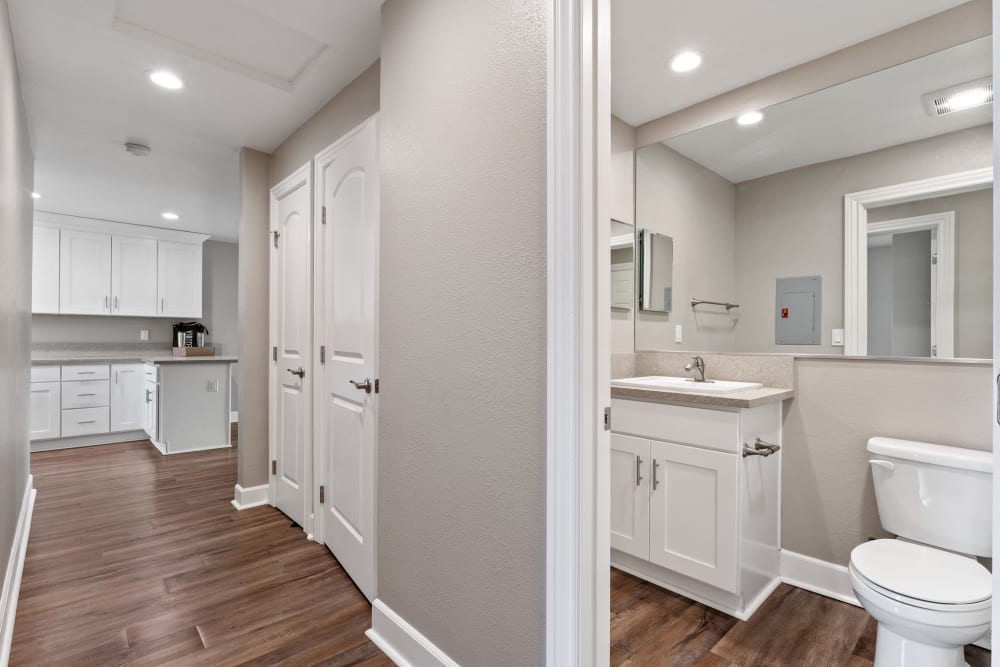 Bathroom and closet off of a hallway with wood-style flooring at Vista Creek Apartments in Castro Valley, California