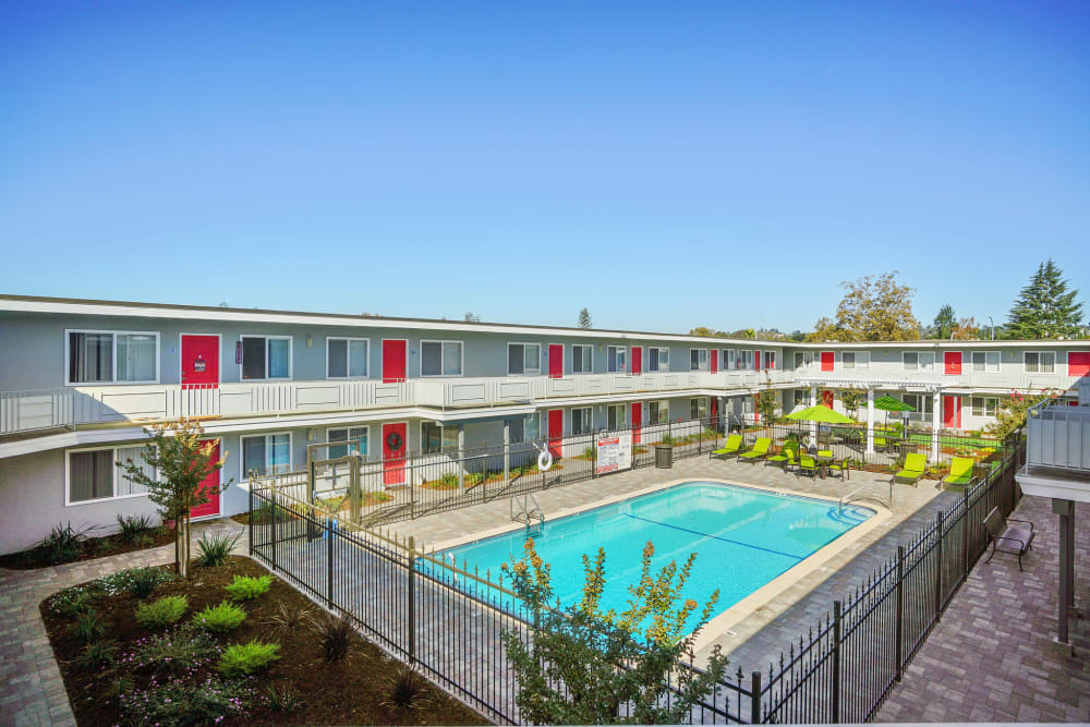 Pool surrounded by lounge chairs and resident patios at Bon Aire Apartments in Castro Valley, California