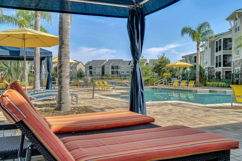 Outdoor lounge seating by the pool at Art Avenue Apartment Homes in Orlando, Florida