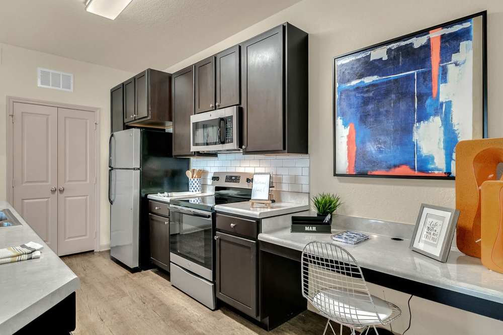 Apartment kitchen with dark wood cabinets and stainless steel appliances at Art Avenue Apartment Homes in Orlando, Florida