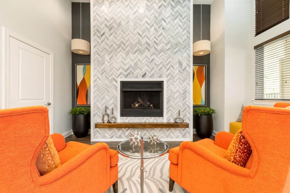 Community lounge with upholstered chairs and fireplace at Art Avenue Apartment Homes in Orlando, Florida