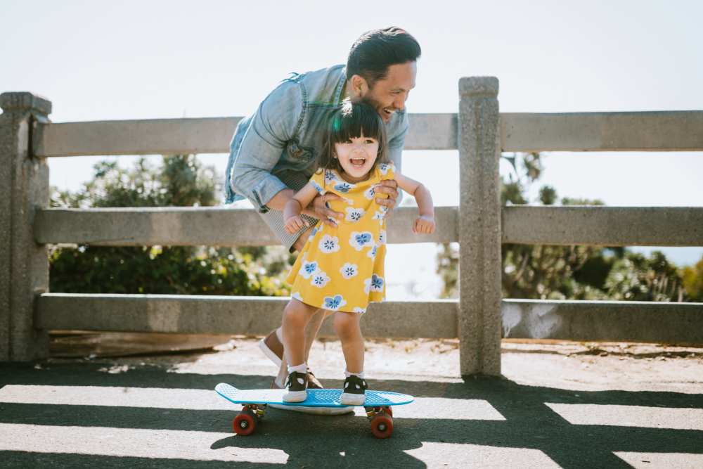 Father teaching child to skateboard near Art Avenue Apartment Homes in Orlando, Florida