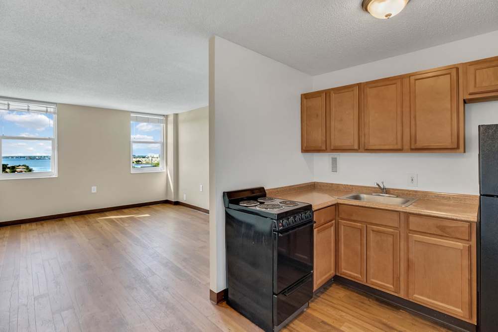 Apartment kitchen with wooden cabinets and hardwood floors at Bay Pointe Tower in South Pasadena, Florida
