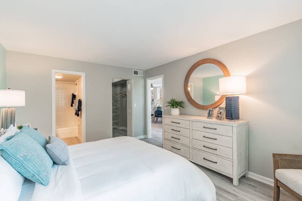 Furnished apartment bedroom with large dresser and circular mirror at Bermuda Cay in Boynton Beach, Florida