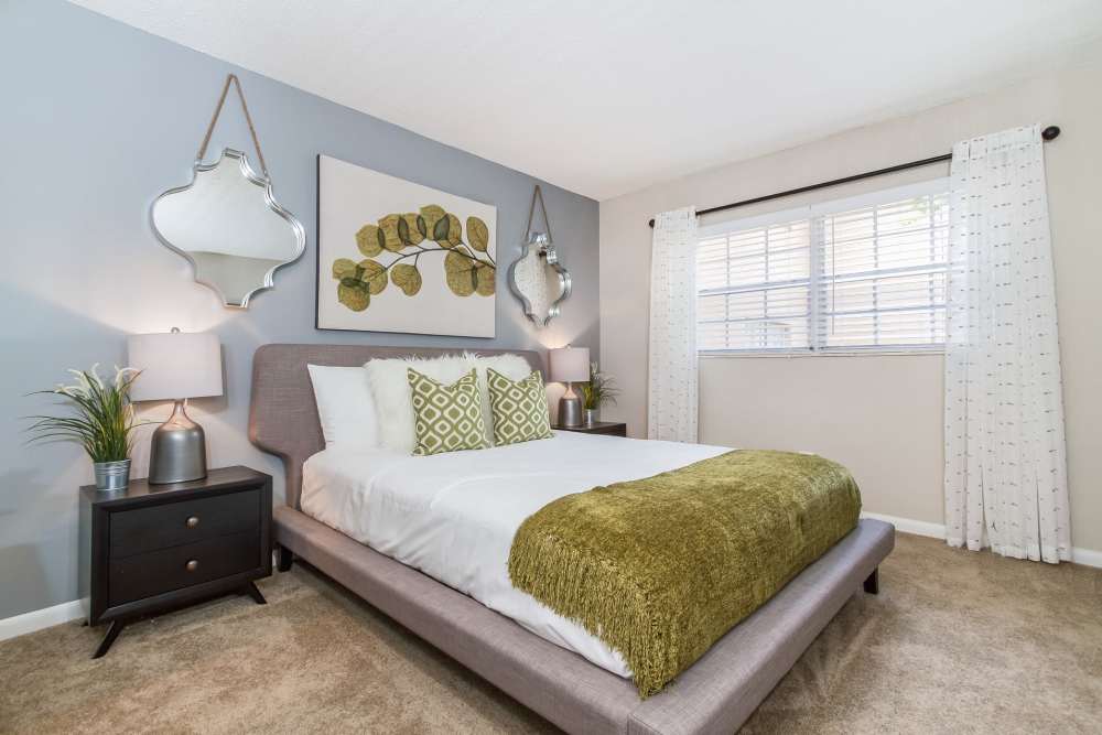 Carpeted apartment bedroom with queen size bed and large window at Central Place at Winter Park in Winter Park, Florida