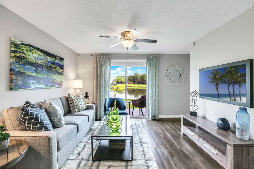 Apartment living room with sofa, coffee table, and large television at Lakeside Central Apartments in Brandon, Florida