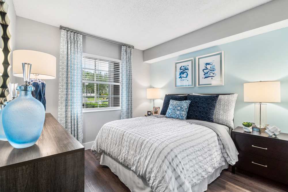 Apartment bedroom with queen-size bed and matching end tables at Boynton Place Apartments in Boynton Beach, Florida