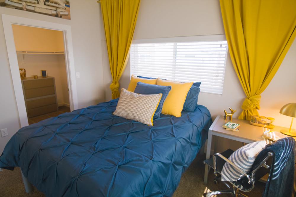 Apartment bedroom with yellow curtains at College Town Fayetteville in Fayetteville, Arkansas