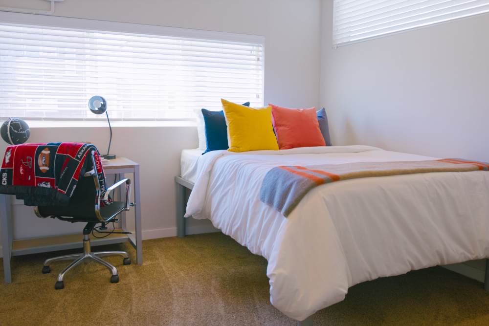 Bedroom with hardwood floors and bed with accent pillows at College Town Fayetteville in Fayetteville, Arkansas