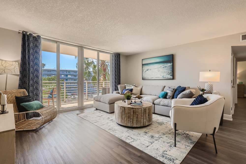 Spacious apartment living room with hardwood floors and balcony access at Waters Pointe in South Pasadena, Florida