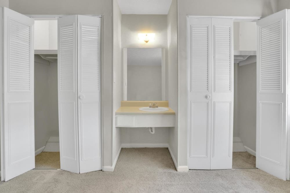A vanity between closets with the doors open in a bedroom at Rivers Edge Apartments in Jonesboro, Georgia