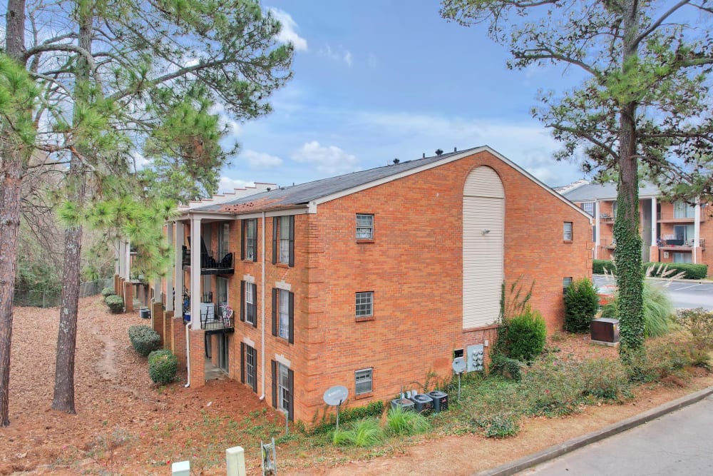 Exterior of a three story apartment building surrounded by trees at Residence at Riverside in Austell, Georgia