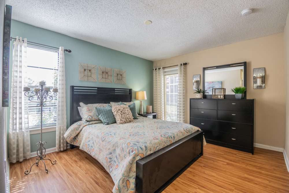 Apartment bedroom with hardwood floors and dresser with mirror at Waterstone At Carrollwood in Tampa, Florida