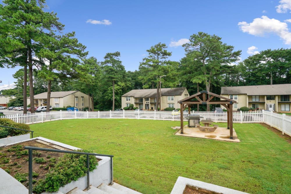 A grassy area with a covered grilling station at Spring Creek Apartment Homes in Decatur, Georgia
