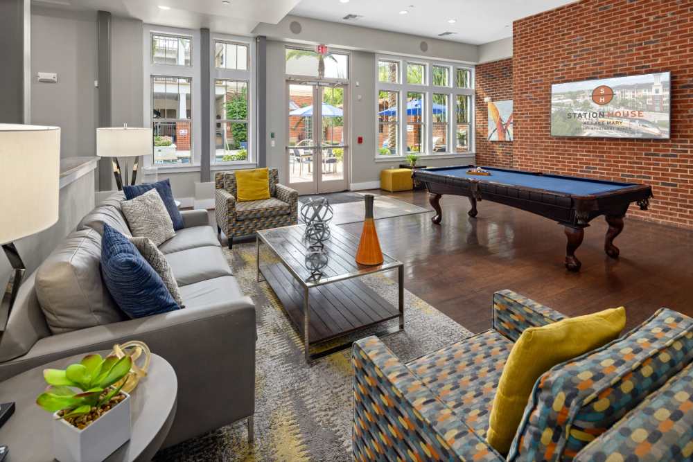 Community lounge with comfy sofas and pool table at Station House at Lake Mary in Lake Mary, Florida