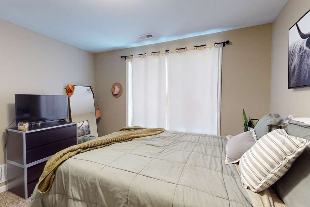 Bedroom with large window and full length mirror at The Quarters at Ames in Ames, Iowa