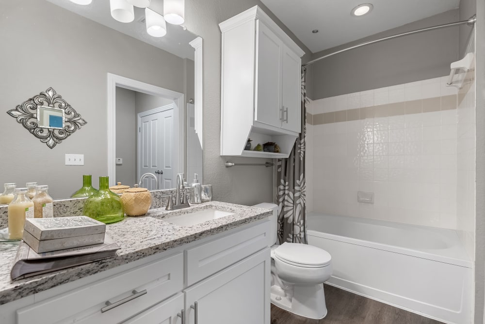Bright bathroom with wood flooring and bathtub at Marquis at Waterview in Richardson, Texas