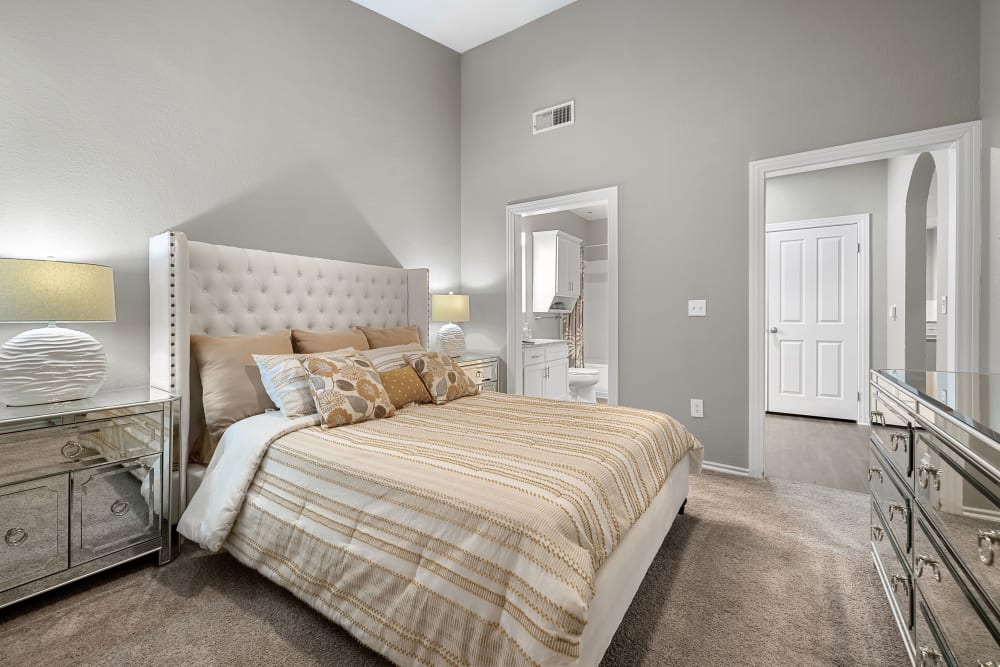 Carpeted bedroom with private bathroom and vaulted ceilings at Marquis at Waterview in Richardson, Texas