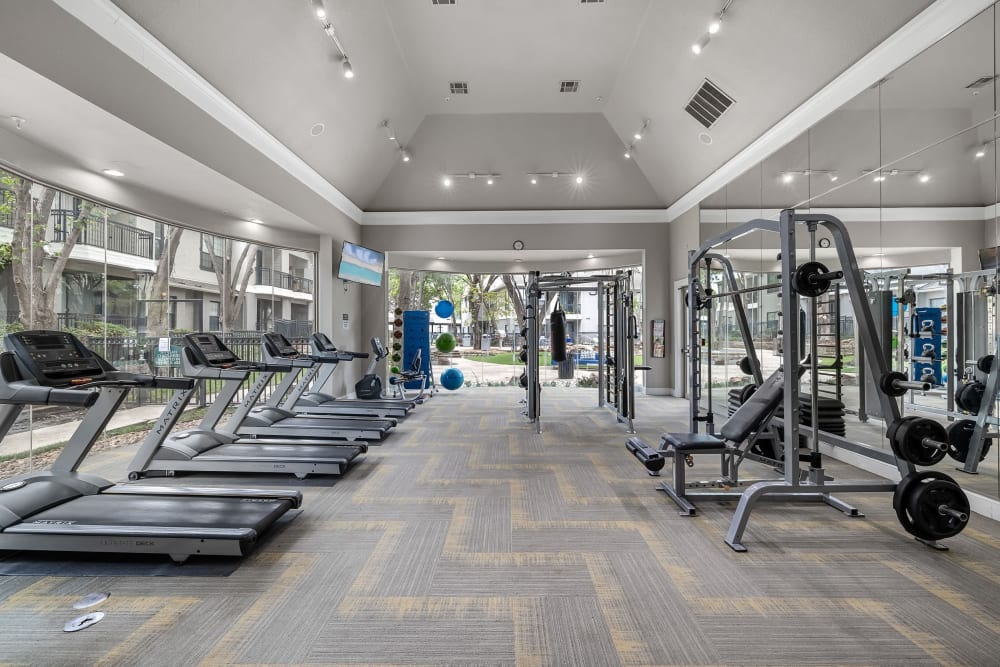 Spacious fitness room with cardio machines and free weights at Marquis at Waterview in Richardson, Texas