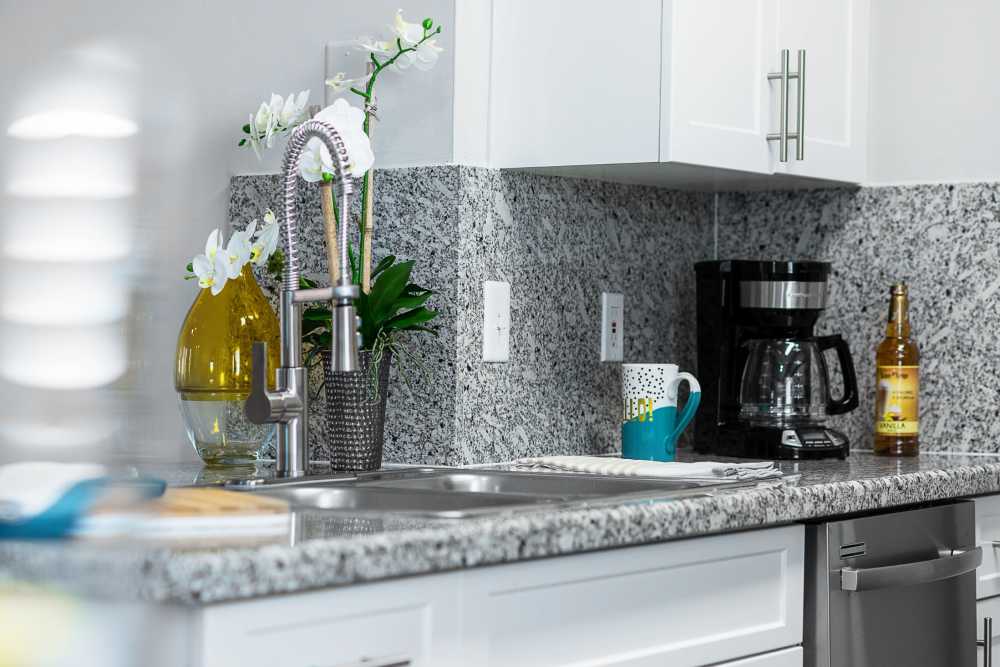 Apartment kitchen with stainless steel sink and granite countertops at Nova Central Apartments in Davie, Florida