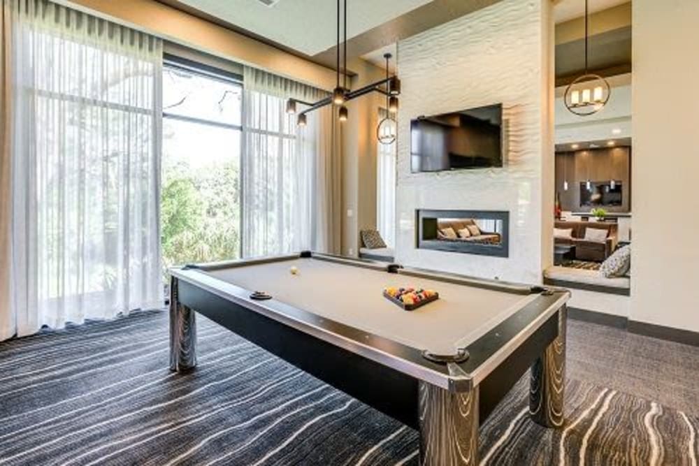 Community clubhouse with pool table and flatscreen television at Addison at Tampa Oaks in Temple Terrace, Florida