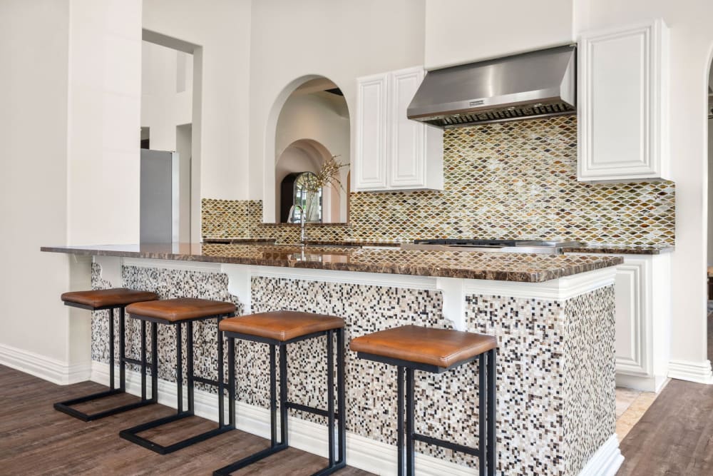 Gourmet kitchen with table island and seats at Olympus Woodbridge in Sachse, Texas