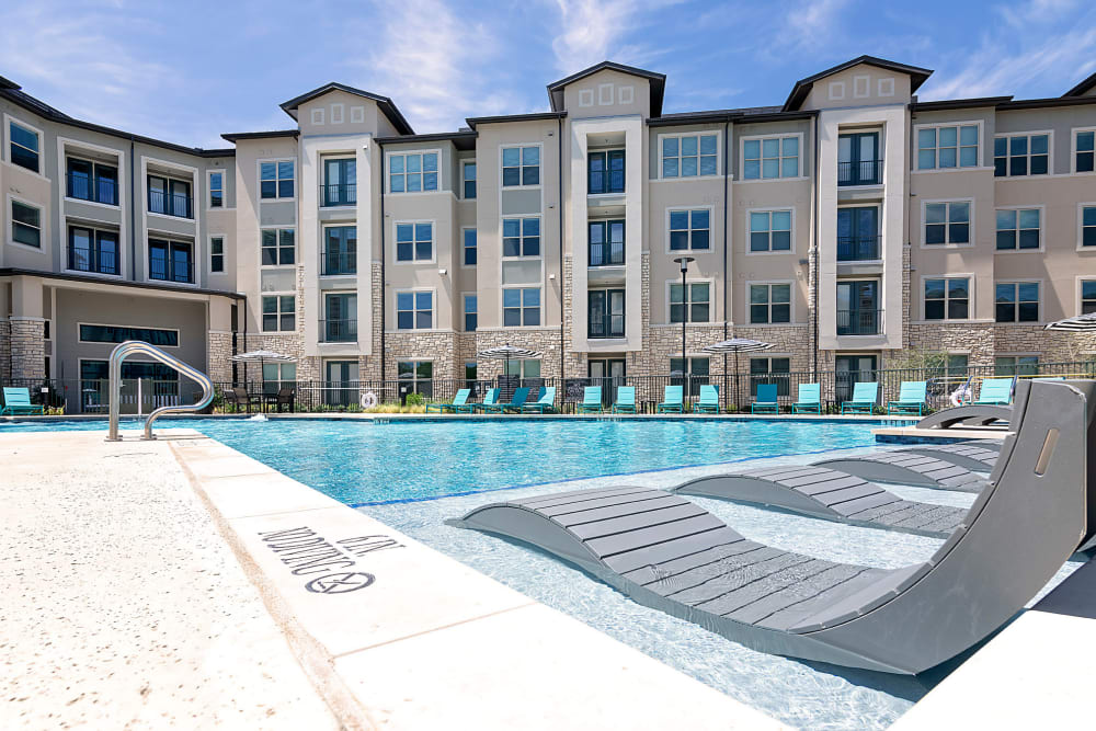 Pool area with exterior view of the building of Auro Crossing in Austin, Texas