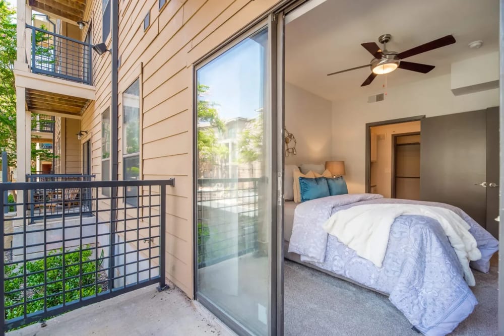 Model bedroom with a sliding glass door at Link at Plano in Plano, Texas