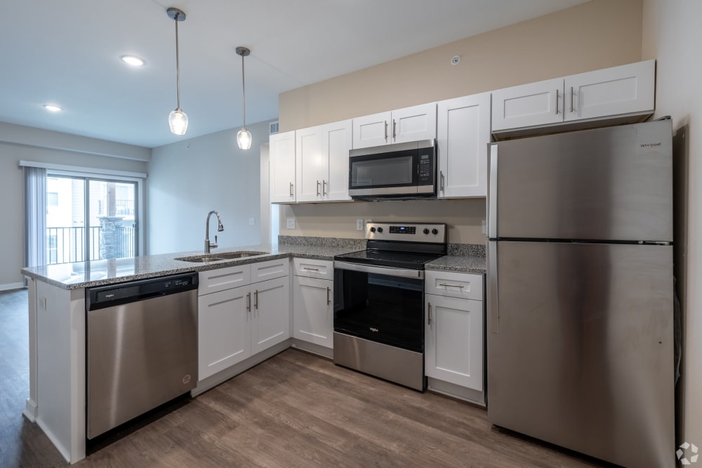 Two BR Apartments in South Kansas City MO - Forest Ridge Villas - Kitchen with Granite-Style Countertops, White Cabinets, Wood-Style Flooring, and Stainless Steel Appliances.