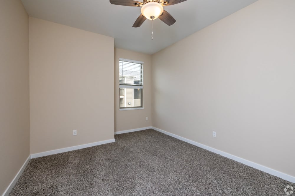 One BR Apartments in South Kansas City MO - Forest Ridge Villas - Bedroom with Carpet Flooring, Ceiling Fan, and Window.