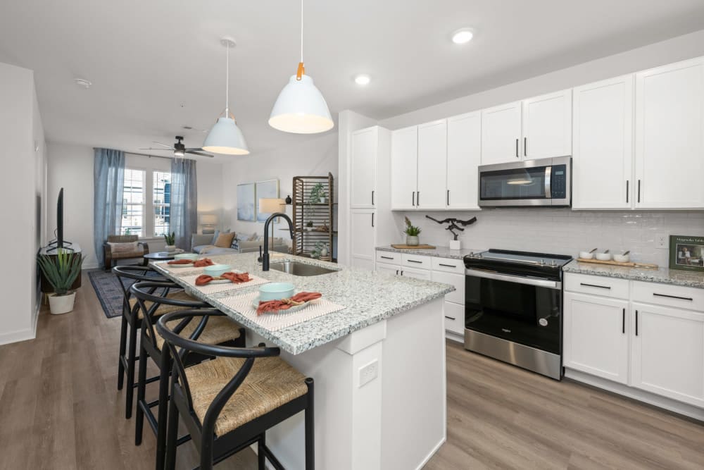 Retirement Homes in Jacksonville, FL - Olea Beach Haven - Kitchen with Stainless-Steel Appliances, Granite-Style Kitchen Island, and White Cabinets