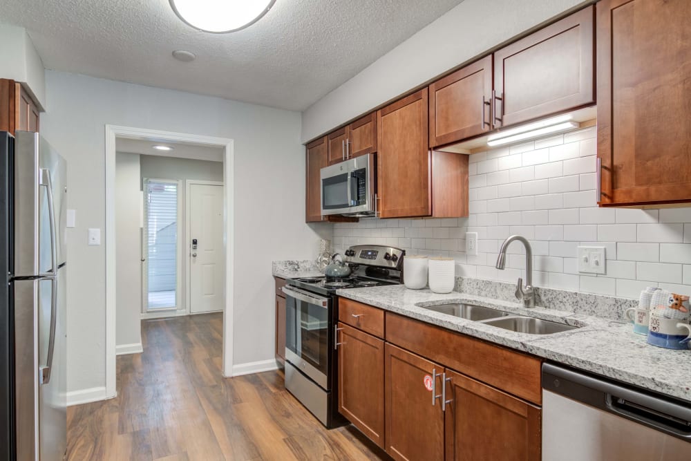 Kitchen featuring stainless steel apartments and wood cabinets at The Lodge on the Chattahoochee Apartments in Sandy Springs, Georgia