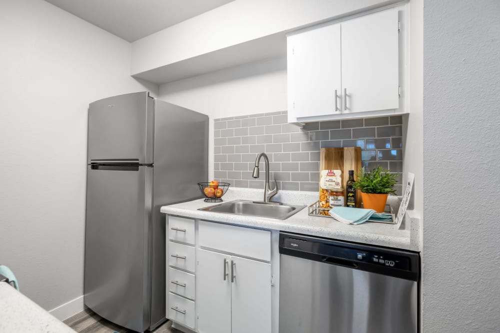 Modern apartment kitchen with white cabinetry, stainless-steel appliances, and tile backsplash at The Mod in Phoenix, Arizona