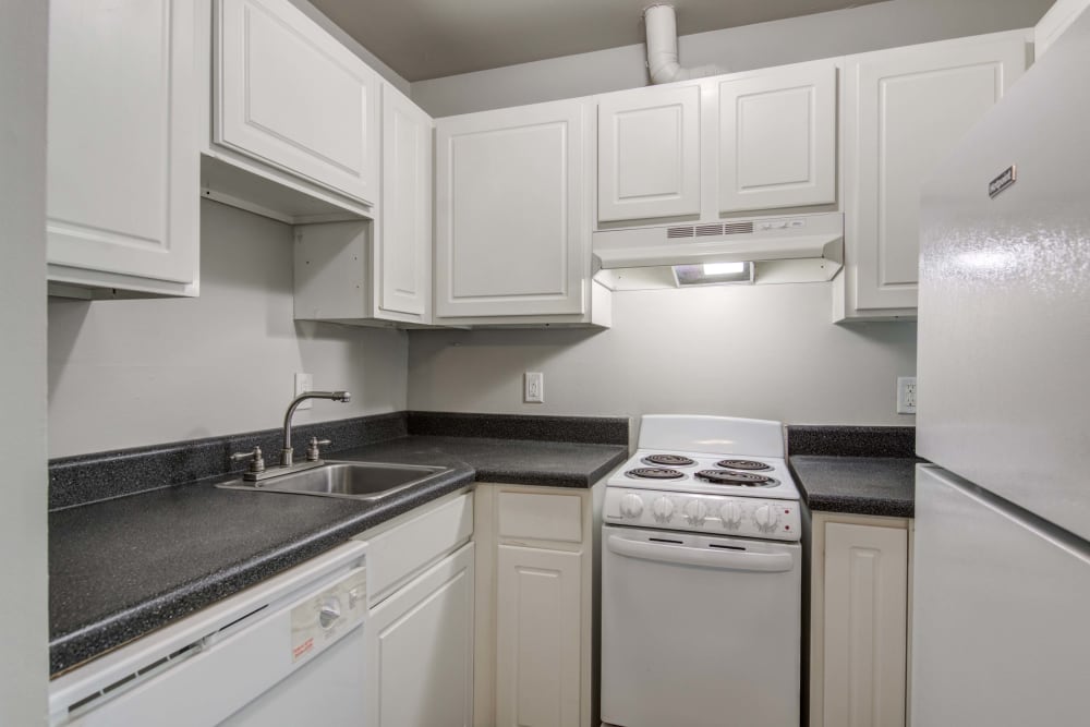 Kitchen with black countertops and white appliances at Woods of Williamsburg Apartments in Williamsburg, Virginia