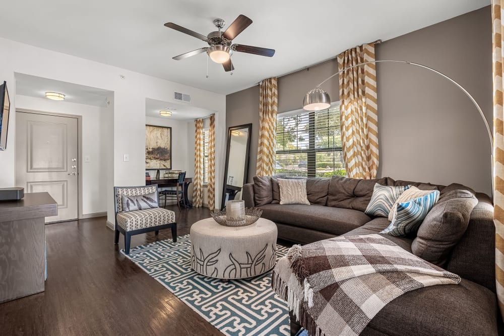 Bright living room with wood flooring and a large rug at Marquis on Lakeline in Cedar Park, Texas