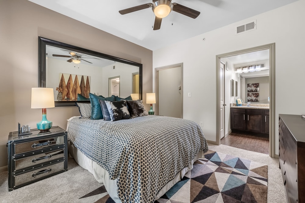 Bright bedroom with a large mirror behind the bed at Marquis on Lakeline in Cedar Park, Texas