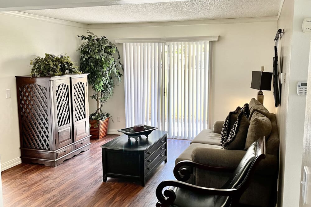 Living room with glass sliding door at Peppertree Place Apartments in Riverside, California
