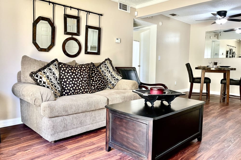 Couch and a comfortable chair in a model home's living space at Peppertree Place Apartments in Riverside, California