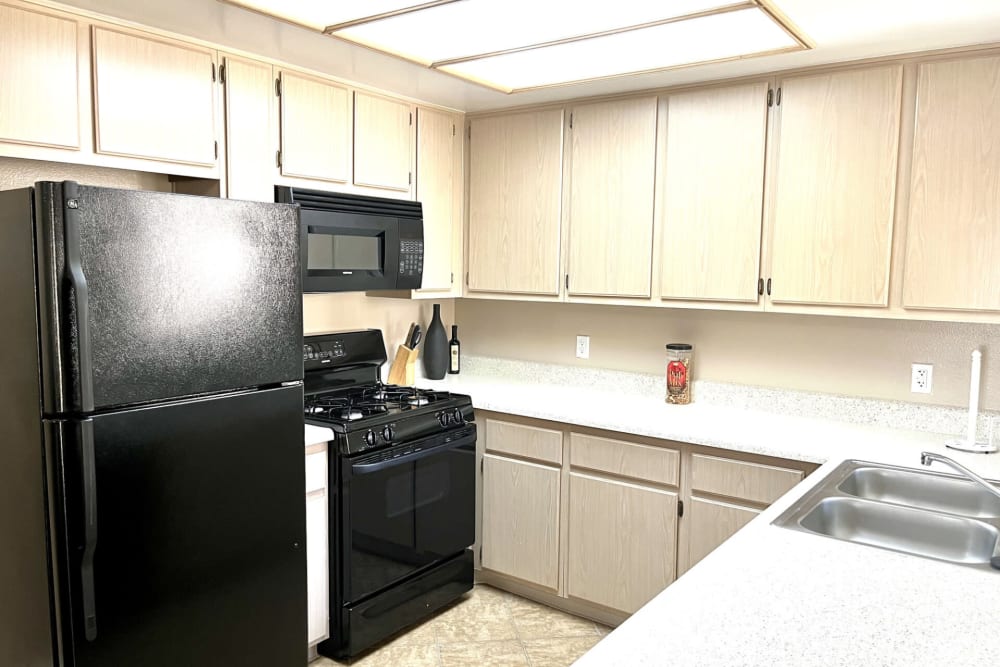 Model kitchen with cabinets at Peppertree Place Apartments in Riverside, California