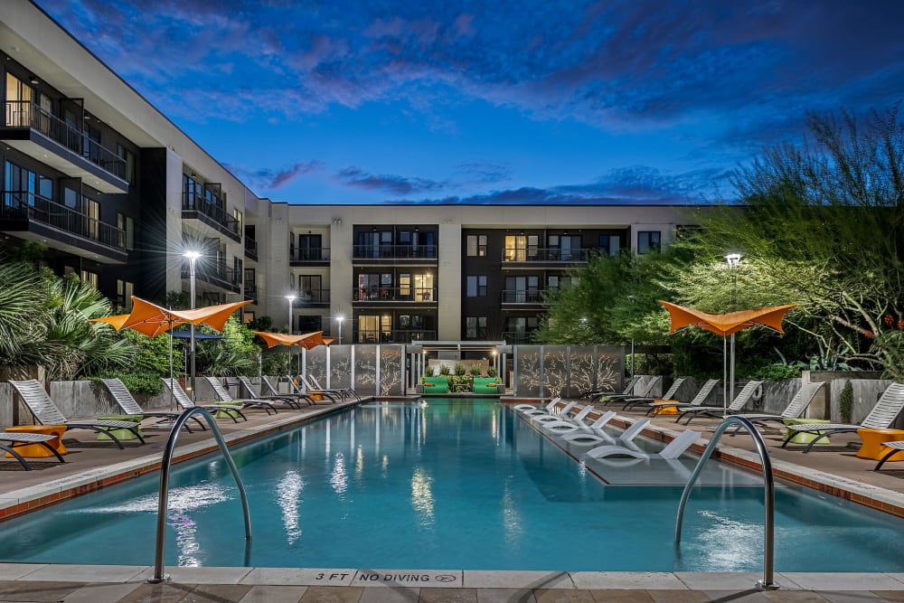 Sparkling resort style pool with lounge chairs at sunset at Marq Uptown in Austin, Texas