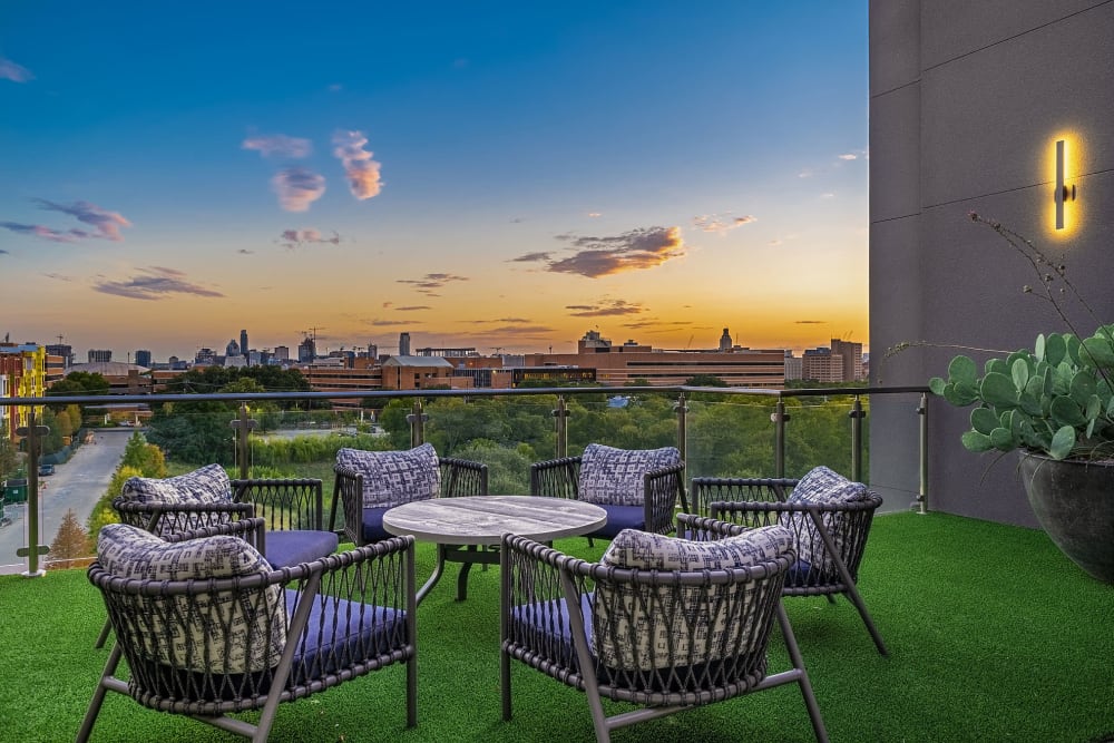 Table with cushioned tables on artificial turf deck overlooking city at sunset at Marq Uptown in Austin, Texas