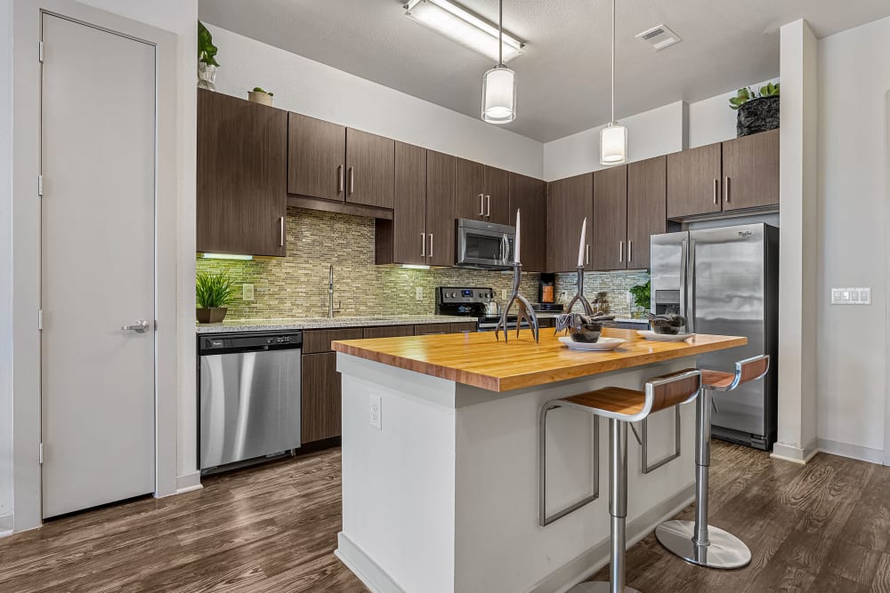 Spacious kitchen with kitchen island and counter stools with dark brown cabinets at Marq Uptown in Austin, Texas
