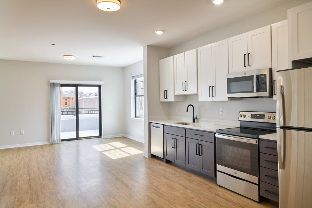 Kitchen and dining area with wood floors and modern appliances in an unfurnished model home at The Seville Apartments in Easton, Pennsylvania