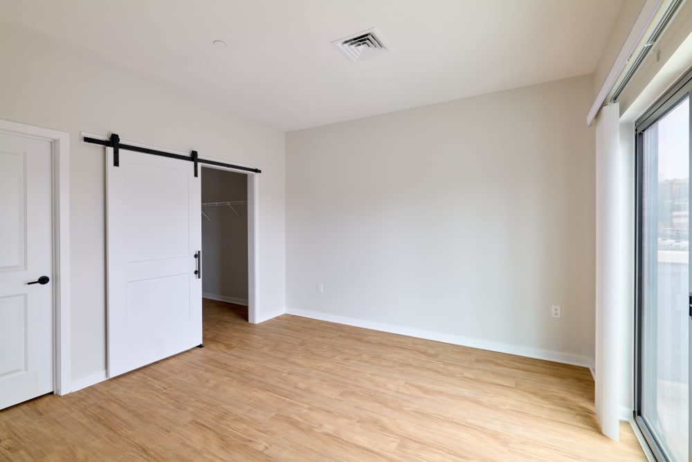 Large bedroom with wood flooring and sliding door closet in an unfurnished model home at The Seville Apartments in Easton, Pennsylvania
