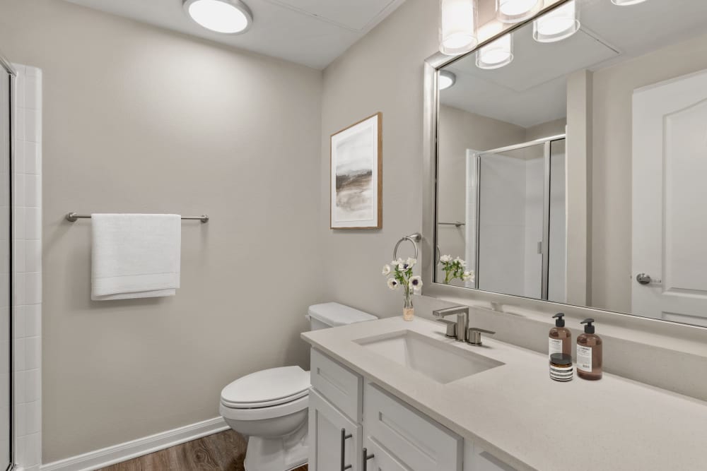 Personal bathroom with a granite countertop and hardwood flooring in a model home at Olympus Las Colinas in Irving, Texas